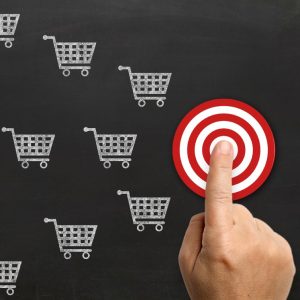 A finger pointing to a target among many shopping carts, symbolizing targeted advertising or marketing strategy.