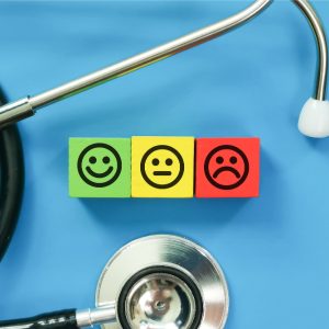 A stethoscope and colorful cubes with smiley faces symbolizing patient satisfaction levels are key in managing your healthcare practice's reputation in a clinical setting.